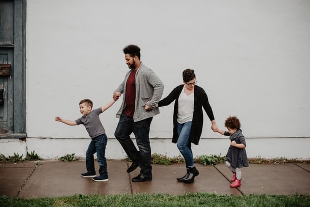 Pai e mãe de mãos dadas com filho e filha de mãos dadas andando juntos