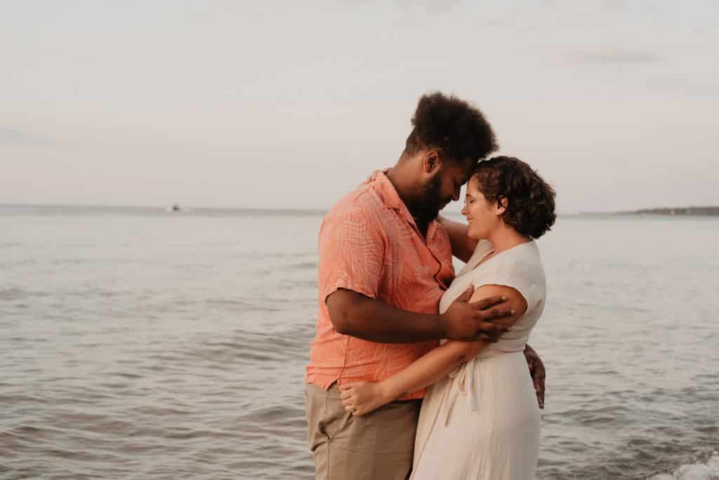 Homem e mulher abraçados e sorrindo ao lado do mar