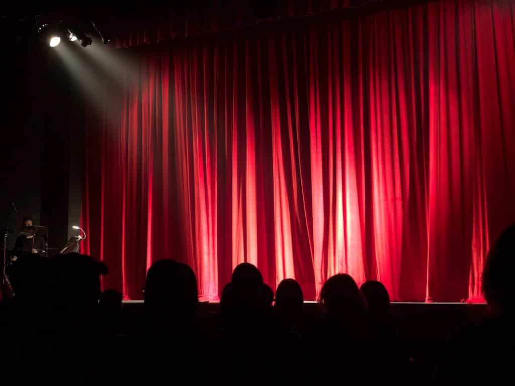 Teatro com as luzes no palco e cortina fechada