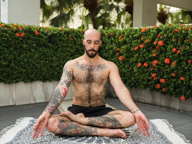 Homem sentado em posição de lótus meditando