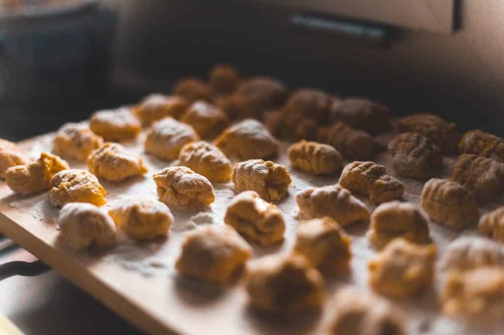 Muitas bolinhas de nhoque em cima de uma tábua com farinha.