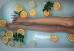 Mulher deitada na banheira com folhas e laranjas em rodelas