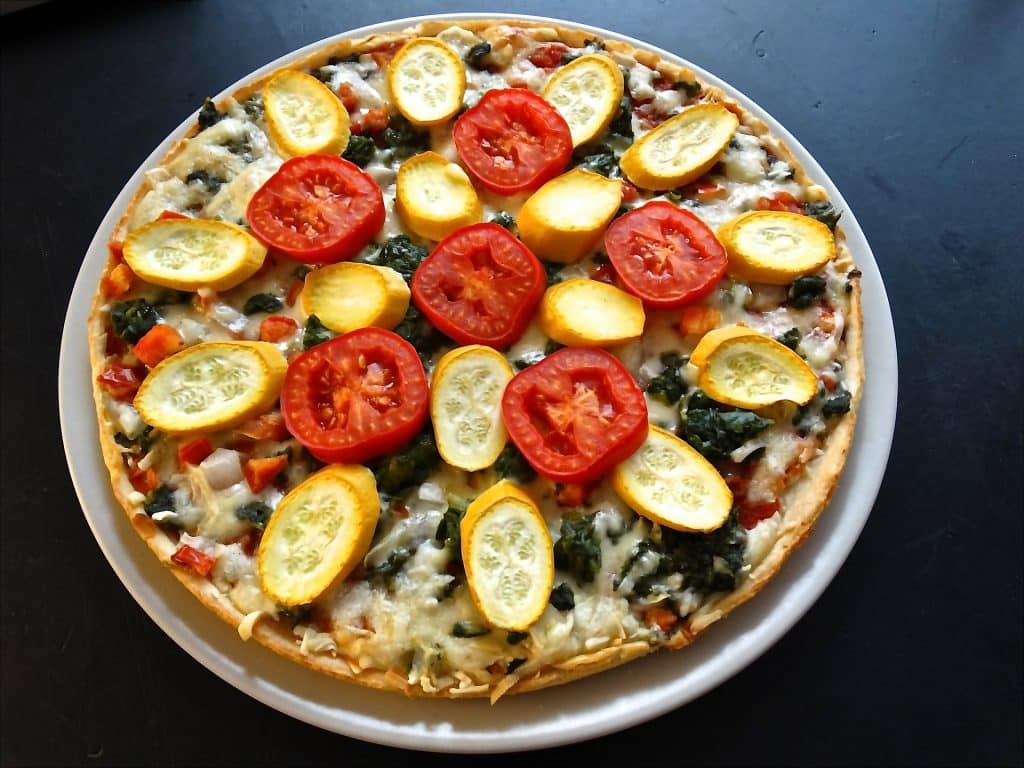 Imagem de uma pizza vegetariana feita com diversos ingredientes e pronta para ser degustada.
