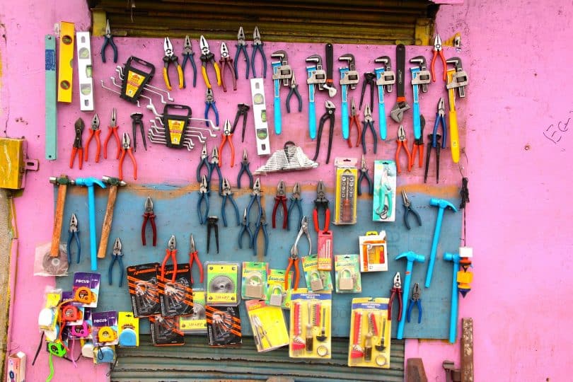 Imagem de um painel na cor rosa e nele está pendurado vários tipos de ferramentas para serem usadas para diversas ocasiões e preparos de materiais.