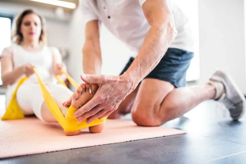 Fisioterapeuta aplicando exercício no pé de paciente