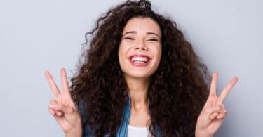 Mulher sorrindo fazendo sinal de paz e amor com as mãos