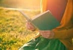 Mãos de mulher segurando livro com sol refletindo