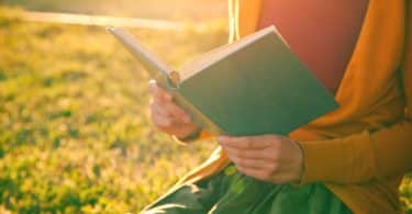 Mãos de mulher segurando livro com sol refletindo