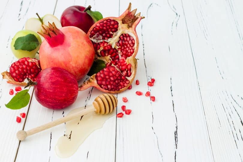 Imagem de frutas como romã, maçã e mel, ingredientes para celebrar o ano novo judaíco.