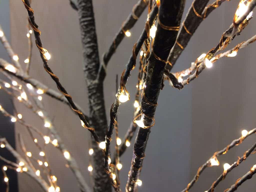 Imagem de uma árvore de Natal feita de galhos decorados com luzes amarelas.