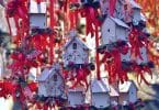 Imagem de várias casinhas de pássaros feita de madeira e pintadas na cor branca e enfeitadas com fitas vermelhas e outros adornos de natal.