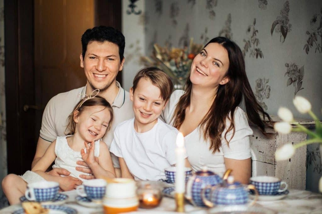 Família sentada à mesa. Todos estão sorrindo.