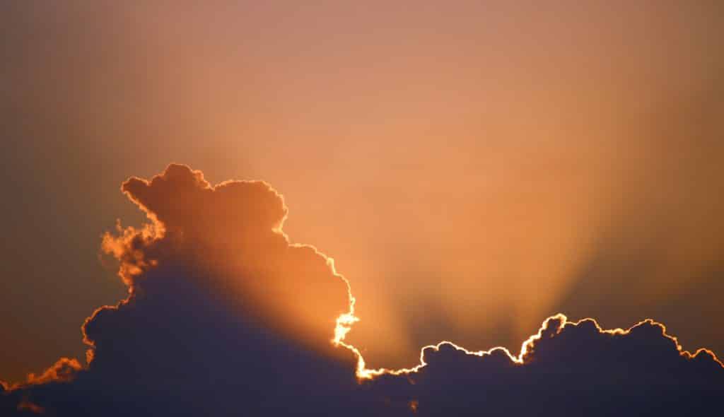 Foto de nuvens com a luz do sol saindo por elas.