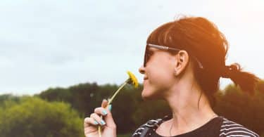 Mulher cheirando uma flor em um jardim