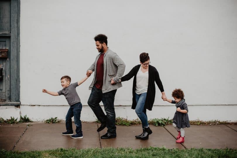 Pais e filhos andando na calçada de mãos dadas