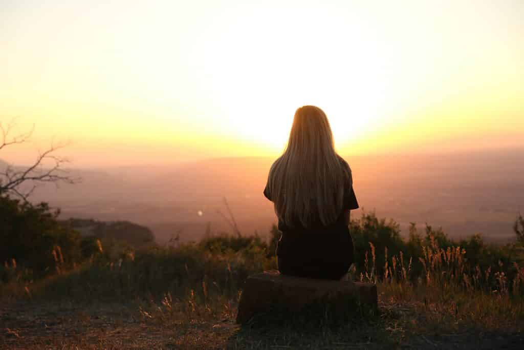 Mulher olhando para  o pôr do sol