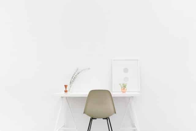 Mesa minimalista com cadeira, quadrinhos e vasos de plantas