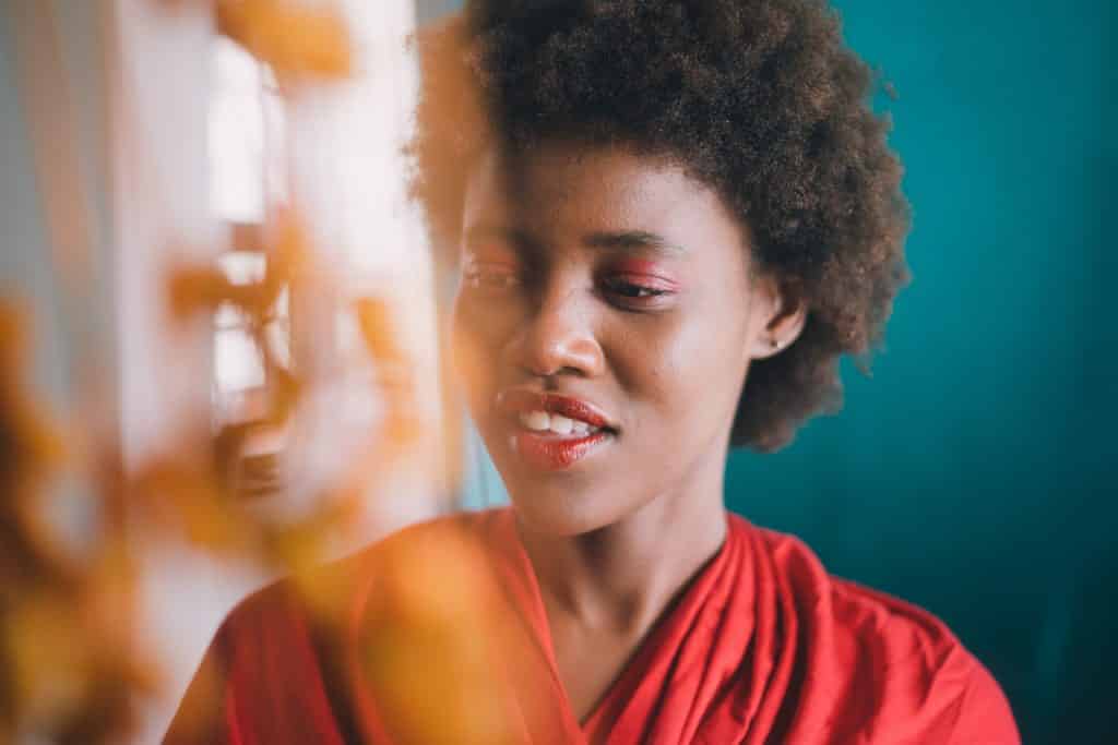 Mulher sorrindo olhando apra baixo ao lado de uma cortina