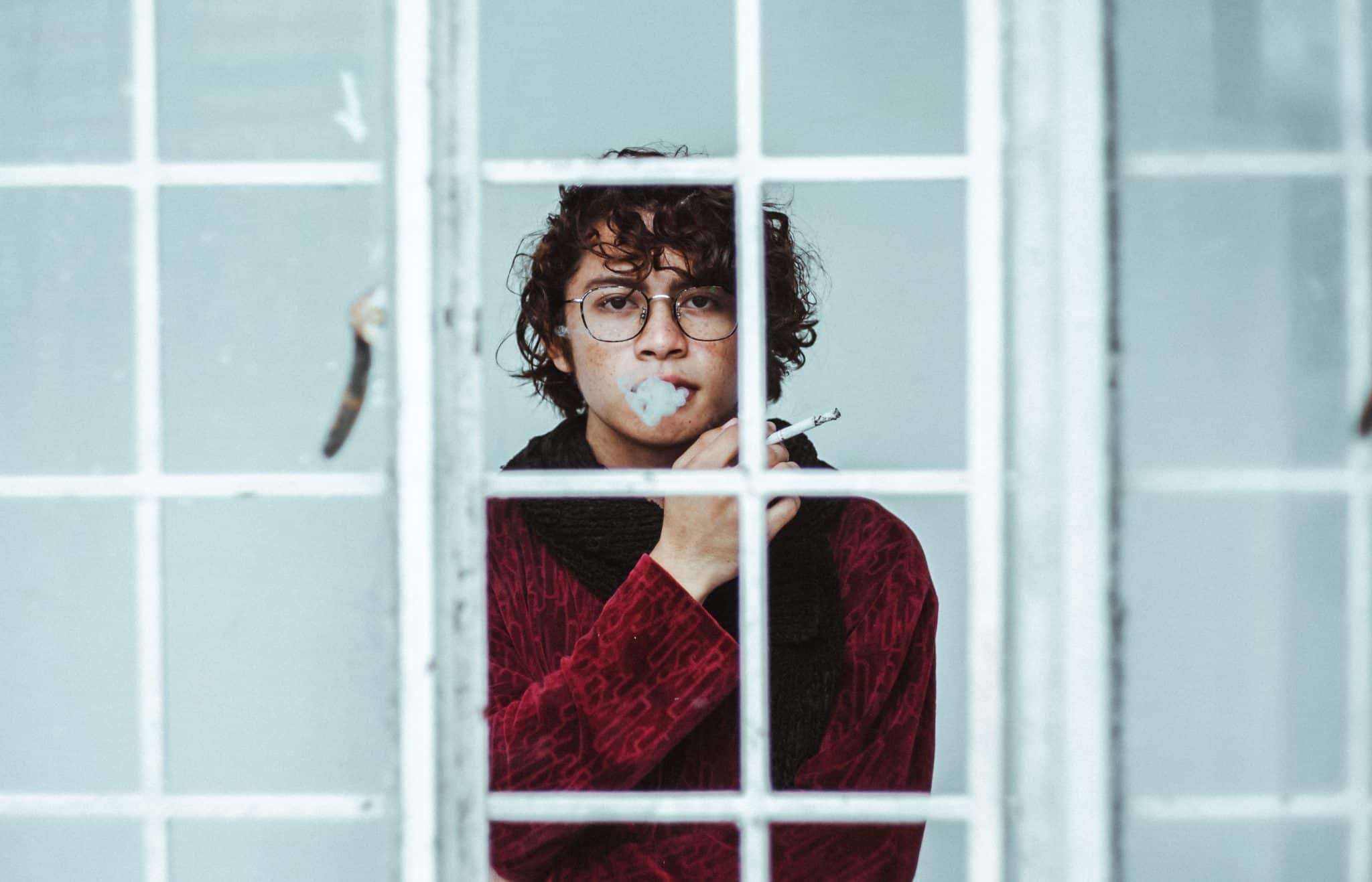 Homem fumando cigarro na janela
