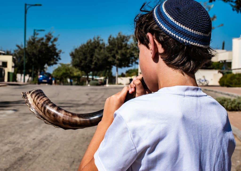Imagem de uma criança judaíca tocando o shofar, um instrumento de sopro muito antigo feito de chifre de carneiro.