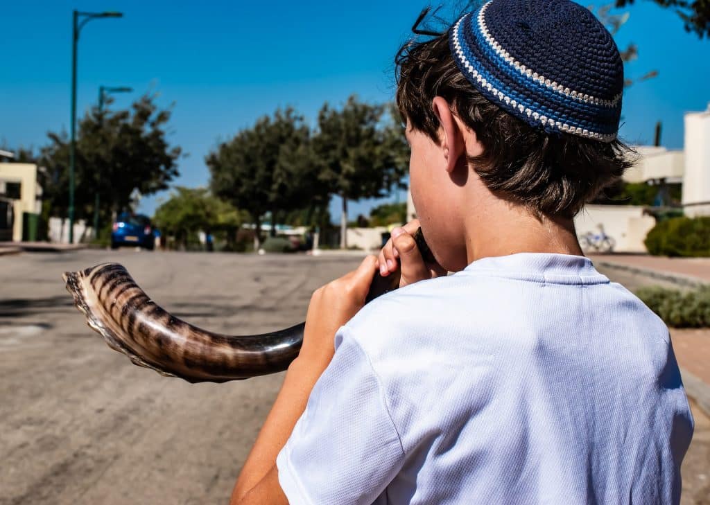 Imagem de uma criança judaíca tocando o shofar, um instrumento de sopro muito antigo feito de chifre de carneiro.