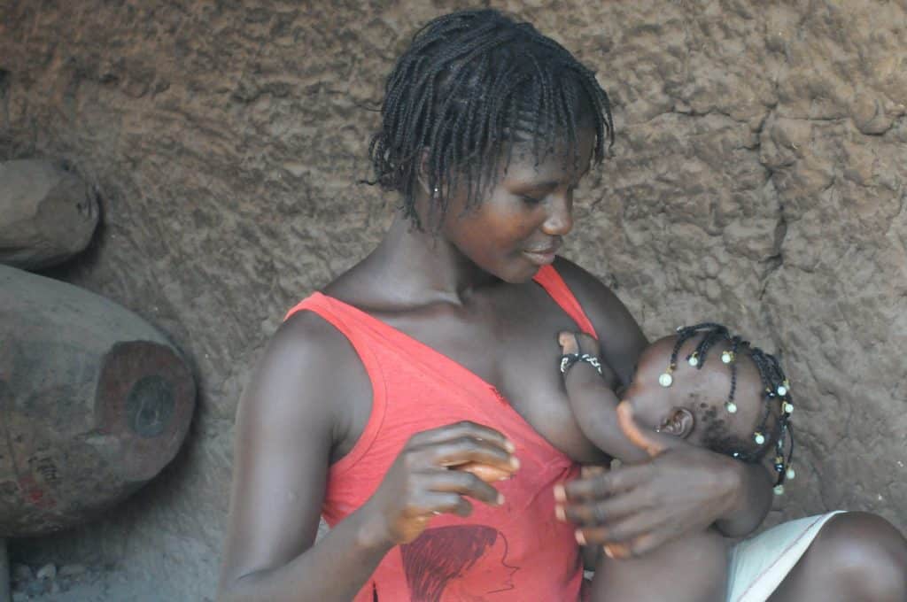 Imagem de um mulher afrodescendente amamentando a sua criança.
