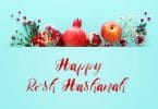 Imagem de várias frutas como romã e maçã decoradas com ramos de flores para compor os rituais para celebrar o ano novo judaíco. À frente dos elementos está escrito em inglês a frase: Happy Rosh HaShaná.