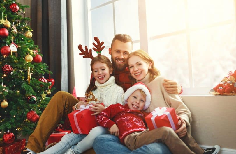 Uma família sentada no sofá enquanto abrem presentes de Natal