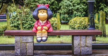 Estátua da personagem Mafalda criada por Pablo Irrgang. Ela está sobre um banco em um parque de Oviedo, na Espanha.