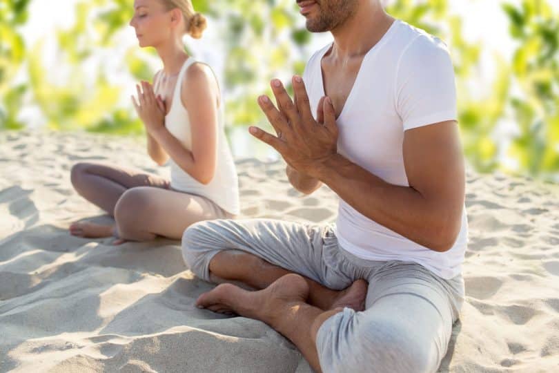 casal fazendo exercícios de ioga sentado ao ar livre