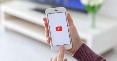 Mulher segurando um celular com o ícone do YouTube na tela.
