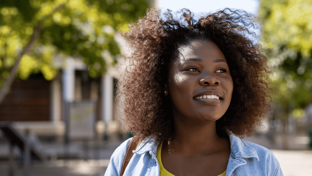 Mulher negra sorrindo enquanto caminha na rua