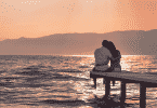 Casal sentado em um deck observando o pôr do sol