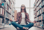 Garota de óculos meditando na biblioteca