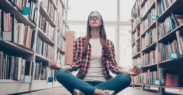 Garota de óculos meditando na biblioteca