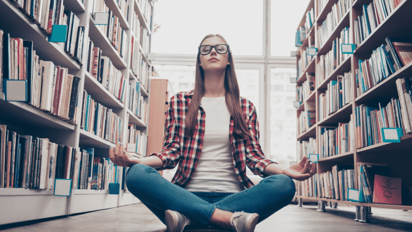 Garota de óculos meditando na biblioteca