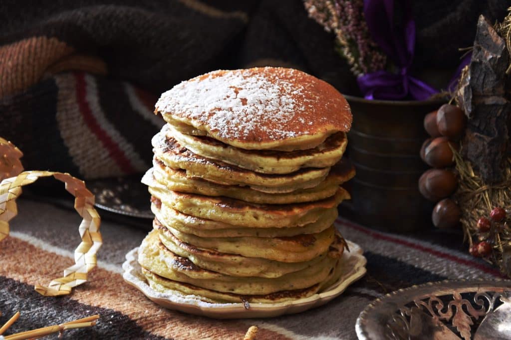 Imagem de um prato contendo várias panquecas já fritas. Elas são feitas com batata-doce.
