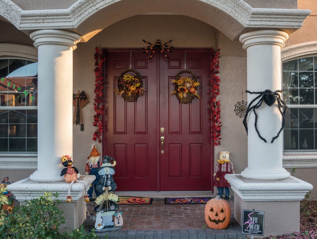 Imagem de uma fachada residencial com uma porta bem grande e toda decorada para a festa de Halloween.