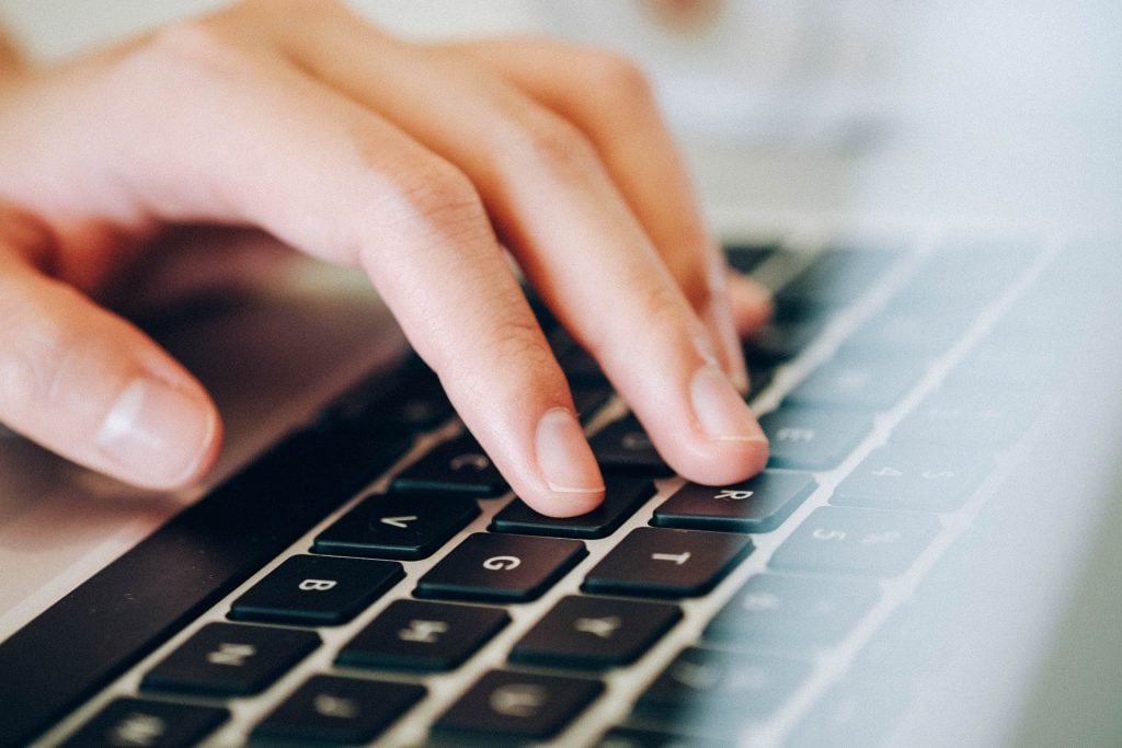 Imagem de uma mão sobre o teclado de um notebook.