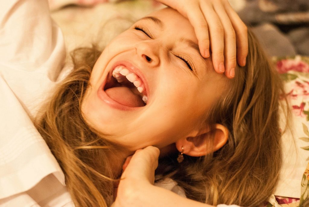 Imagem de uma linda garotinha deitada com um sorriso contagiante.