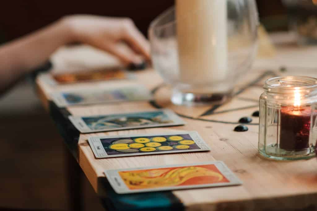 Cartas de tarot e velas sobre mesa de madeira.