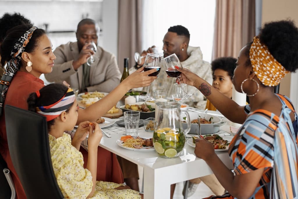 Família, composta por adultos e crianças, à mesa durante um jantar de Dia de Ação de Graças.