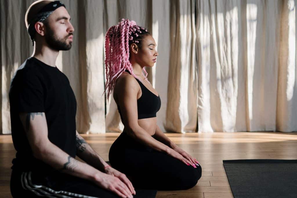 Um homem e uma mulher sentados no chão meditando