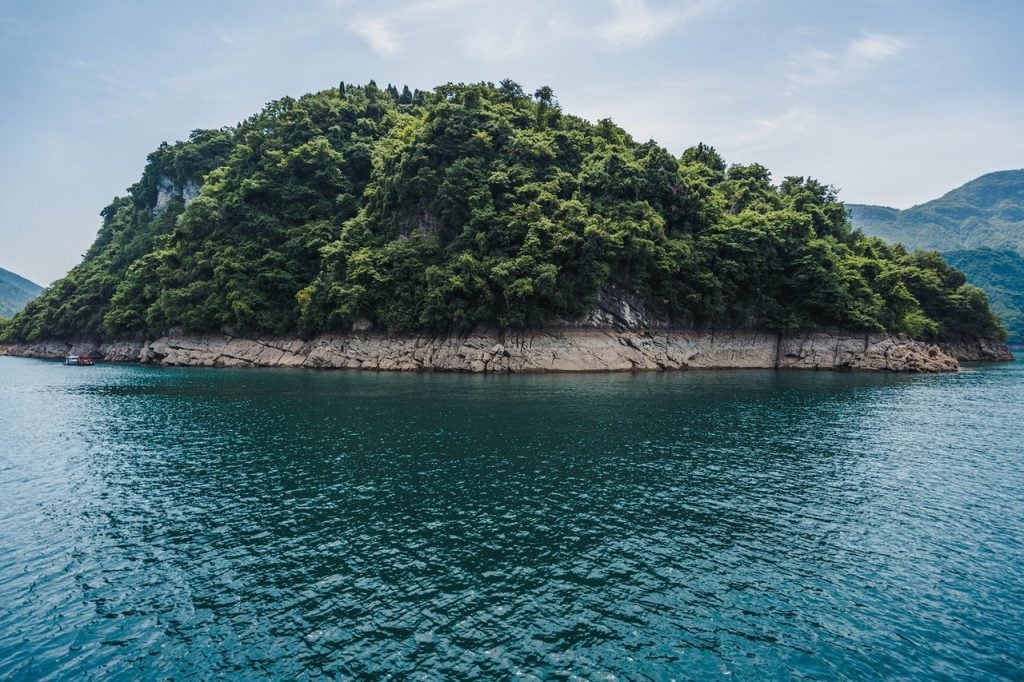 Ilha arbórea com mar ao redor.