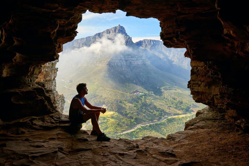 Homem sentado dentro de uma caverna em uma montanha.