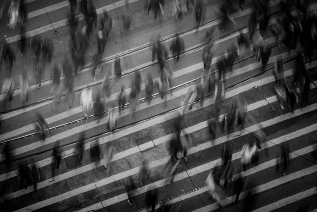 Vultos de pessoas atravessando uma rua.