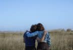 Duas pessoas abraçadas em um campo com gramado alto