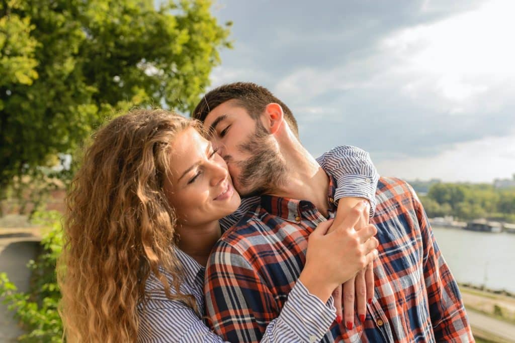 um homem beijando a bochecha de uma mulher enquanto ela está sorrindo 