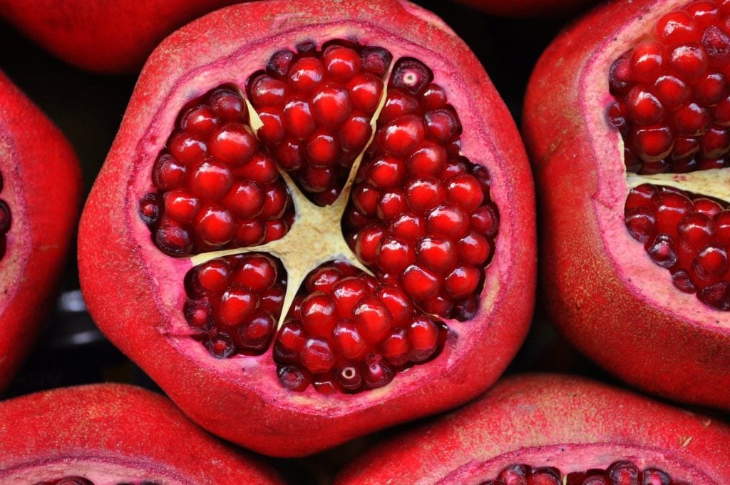 Imagem de várias romãs cortadas ao meio, suas sementinhas estão bem vermelhas.
