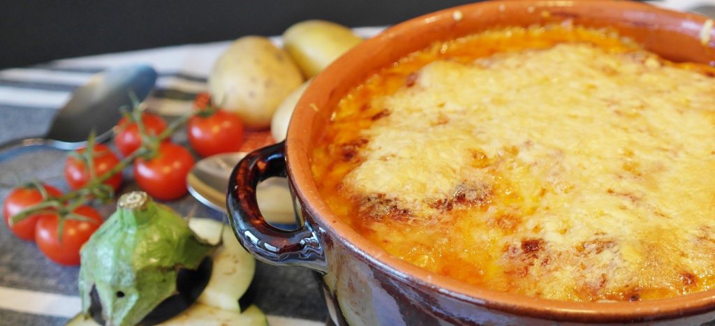 Imagem de uma caçarola cheia de escondidinho de frango cremoso com batata doce gratiando com queijo.